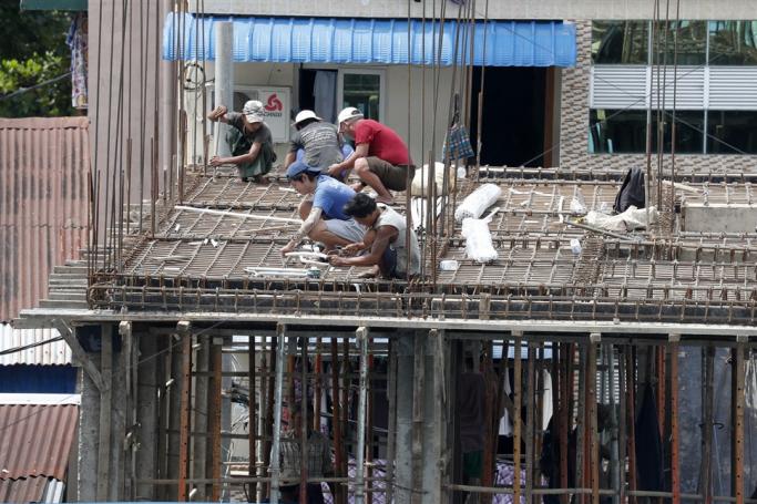 Workers install steel beam reinforcement at the construction site in Yangon, Myanmar. Photo: EPA