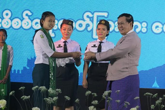 Union Minister U Thein Swe (right) presents a citizenship scrutiny card to a school girl. Photo: MNA