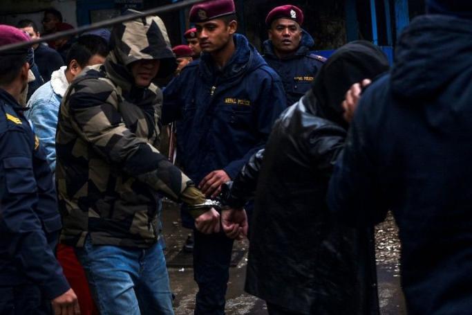 Chinese nationals, arrested on suspicion of operating a large-scale cyber fraud operation, are being escorted to a police vehicle for deportation in Kathmandu on January 8, 2020. (AFP Photo/PRAKASH MATHEMA) 