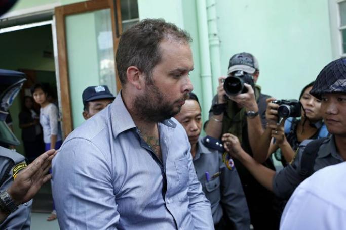 New Zealand citizen Philip Blackwood (C) is escorted by Myanmar policemen after his hearing at the court in Yangon, Myanmar, January 2, 2015. He and two Myanmar citizens, who ran a bar in Yangon, are accused of insulting Buddhism by using an image of the Buddha wearing DJ headphones on their flyer promoting a drinks event. Photo: Lynn Bo Bo/EPA 
