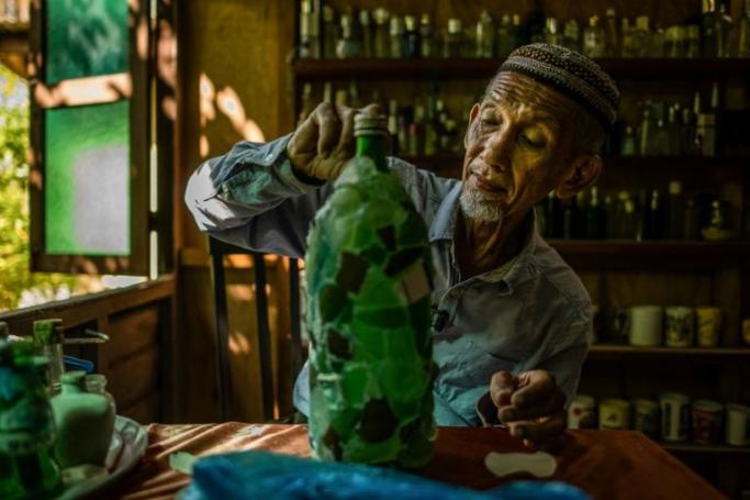 This picture taken on September 12, 2020 shows Tengku Mohamad Ali Mansor decorating pieces of broken glass he found along the shore of beaches in his bottle museum in Penarik village in the Setiu district of the eastern Malaysian state of Terengganu. Photo: AFP