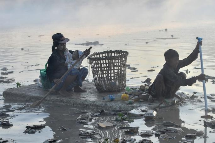 This photo taken on January 14, 2023 shows waste collectors paddling polystyrene boats as they look for plastic and glass to recycle in Pazundaung Creek in Yangon. Photo: Sai Aung Main/AFP