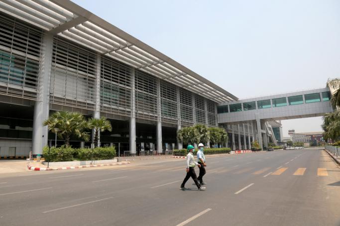 (File) Two men wearing face masks amid concerns over the spread o COVID-19 novel coronavirus cross an empty street outside Yangon International Airport in Yangon on April 8, 2020. Photo: Sai Aung Main/AFP