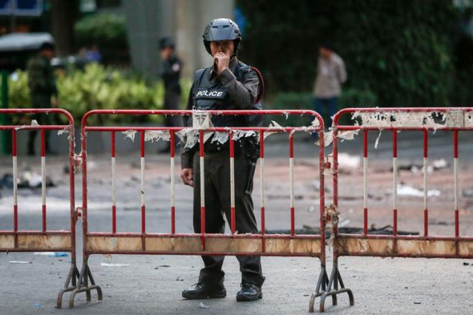 A police officer stands behind a fence as investigative work is done at the scene where a bomb was detonated on 17 August outside Erawan Shrine in central of Bangkok, Thailand, 18 August 2015. Photo: Diego Azubel/EPA
