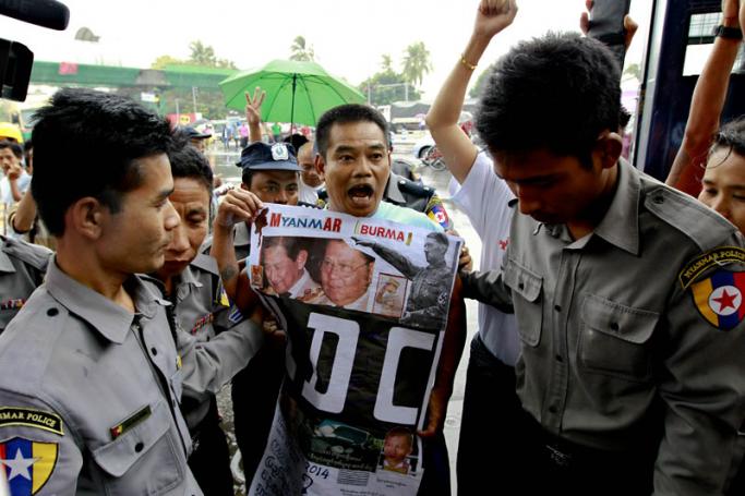 Myanmar dissident Htin Kyaw (C) holds a poster on which he is questioning the Myanmar government on the country's poverty and the path of change, as he arrives at a court for his trial, in Yangon, Myanmar, 18 September 2014. Photo: Lynn Bo Bo/EPA
