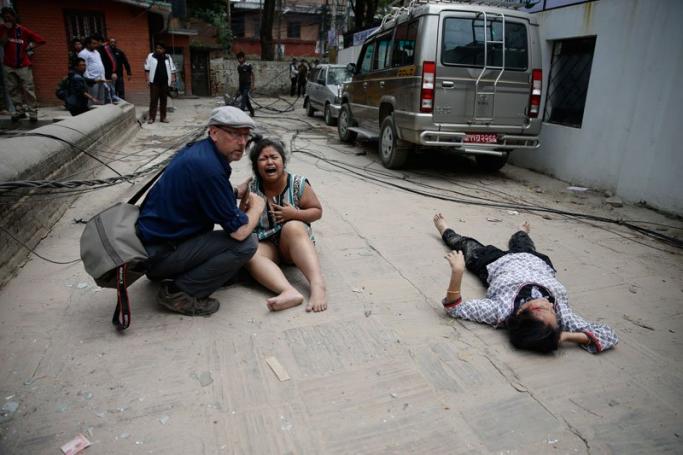 A man comforts a woman next to a seriously injured person on the ground after an earthquake hit Nepal, in Kathmandu, Nepal, 25 April 2015. A 7.9-magnitude earthquake rocked Nepal destroying buildings in Kathmandu and surrounding areas, with unconfirmed rumours of casualties. Photo: Narendra Shrestra/EPA

