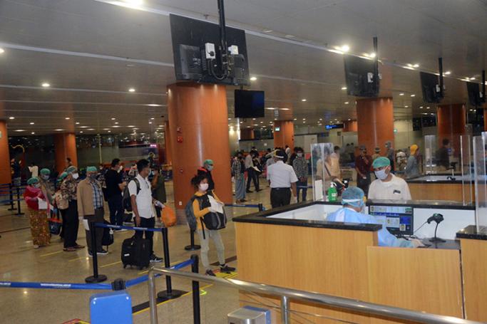 Myanmar returnees from India are queuing for immigration process at Yangon International Airport yesterday. Photo: MNA