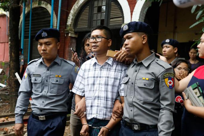 Detained Reuters journalist Wa Lone (C) is escorted out of court by police after his trial in Yangon, Myanmar, 16 July 2018. Photo: Nyein Chan Naing/EPA
