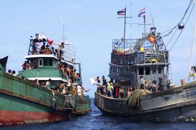 Muslim Rohingya migrants, believed to have come from Myanmar and Bangladesh (L), receive food, water and other aid supplies from a Thai fishing boat (R) in the Andaman Sea close to Malaysia, southern Thailand, 14 May 2015. Photo: EPA
