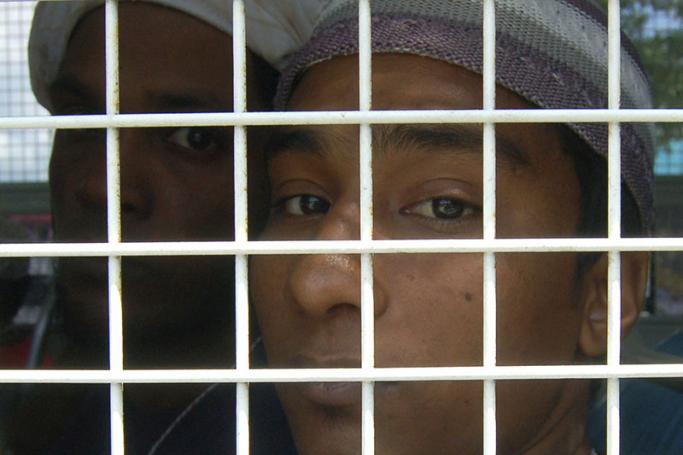 Muslim migrants from Bangladesh looks on behind bar on a police truck, days after they were rescued along with ethnic Rohingya refugees following the human trafficking crackdown, at the district hall in Rattaphum district, Songkhla province southern Thailand, 12 May 2015. Photo: EPA
