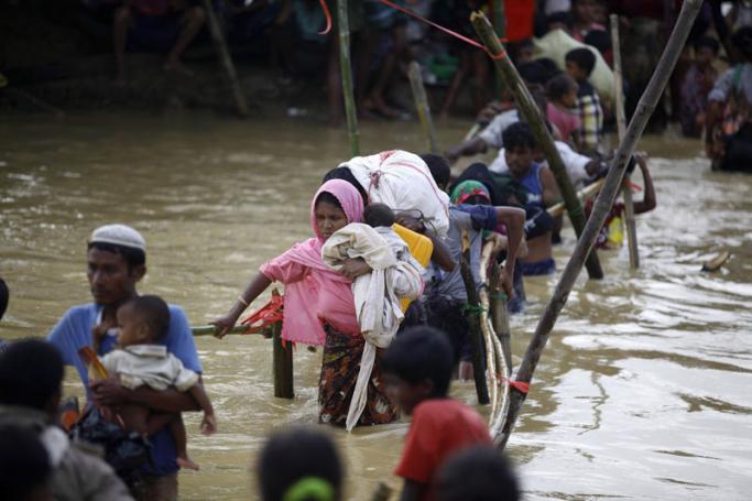 Rohingya refugees walk on a bamboo-made bridge to cross a small canal as they move from their temporary camp due to rain ruining most of their makeshift tents, near Kutupalong, Ukhiya, Bangladesh, 20 September 2017. Photo: EPA-EFE

