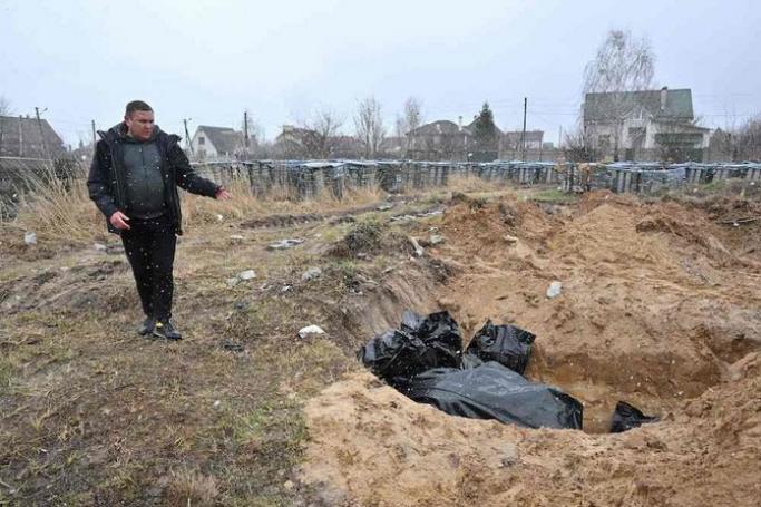 A man gestures at a mass grave in the town of Bucha, northwest of the Ukrainian capital Kyiv on April 3, 2022. Photo: AFP