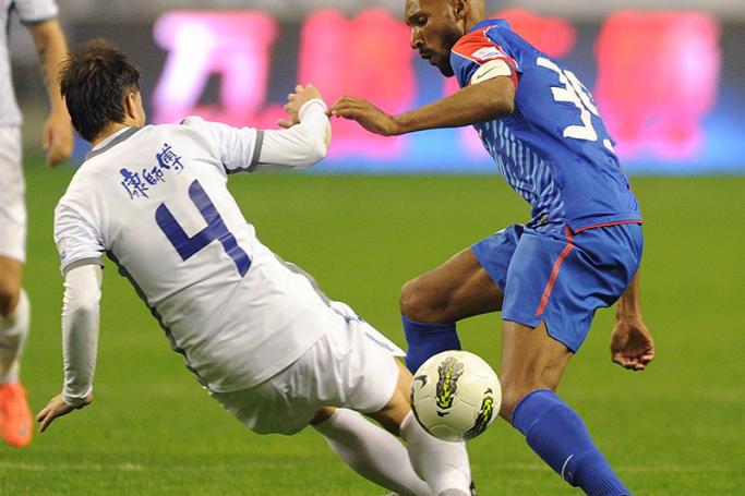 French International football player Nicolas Anelka (R) from the Shanghai Shenhua club fights for the ball against Australian footballer Milan Susak of Tianjin Teda club during the match of football Chinese Super League in Shanghai on April 13, 2012. Tianjin Teda won 1-0. Photo: LIU JIN/AFP
