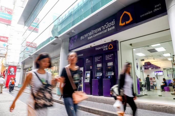 People walk past a branch of Siam Commercial Bank (SCB) in central Bangkok Thailand. Photo: EPA
