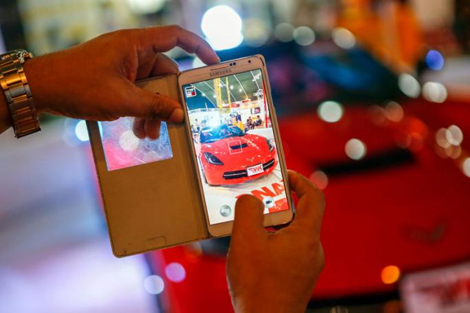 A visitor uses his mobile phone camera to take photograph of a 2014 Chevrolet Corvette car at Myanmar's international automotive parts, accessories and servicing expo 'MYANAUTO 2015' exhibition in Yangon, Myanmar. Photo: Lynn Bo Bo/EPA
