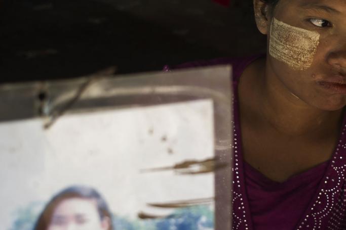 (File) This photo taken on June 30, 2016 shows Mar Tuu holding a photograph of her sister Kyi Pyar Soe on the outskirts of Yangon. Enticed by work in China, hundreds of poor young Myanmar women are instead being duped into marriage, and left to scramble to get back across remote borders before they are forced into life with husbands they have never met. Photo: Ye Aung Thu/AFP