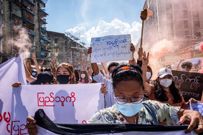 Women carry banners and a burning torch as they march during a demonstration against the military coup in Yangon on July 14, 2021.  Photo: AFP