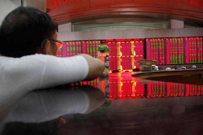 A stock display is reflected on a tabletop while investors monitor and trade stocks at a securities exchange house in Shanghai, China. Photo: Qilai Shen/EPA
