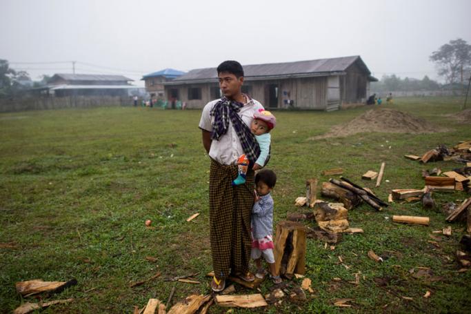 An internally displaced man and his children stand on a field at a temporary shelter in Danai, Kachin state. Photo: Ye Aung Thu/AFP