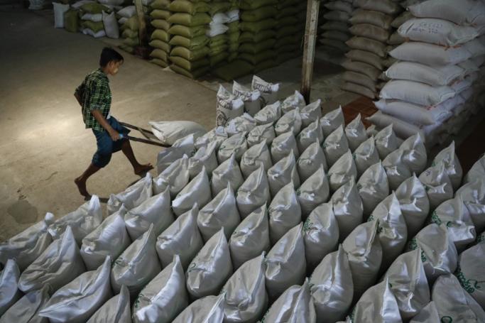 Myanmar man carries a rice bag on a cart as he works at a rice mill in Moulmeingyun township of Ayeyarwaddy region, Myanmar. Photo: EPA