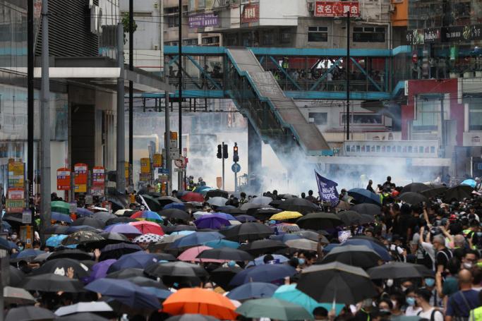 Tear gas is seen in the background as police try to disperse protesters during a rally against the implementation of a new national security law in Causeway Bay, Hong Kong, China, 24 May 2020. Photo: Jerome Favre/EPA