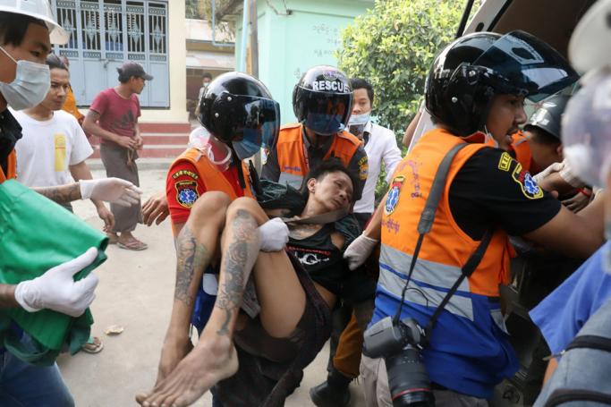 A wounded man is carried by a medical team after security forces opened fire on protesters during a demonstration against the military coup in Mandalay on February 20, 2021. Photo: AFP