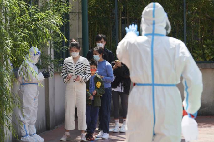 Community volunteers wearing personal protective equipment guide residents queuing to get tested for the Covid-19 coronavirus in a compound during a Covid-19 lockdown in Pudong district in Shanghai on April 17, 2022. Photo: AFP