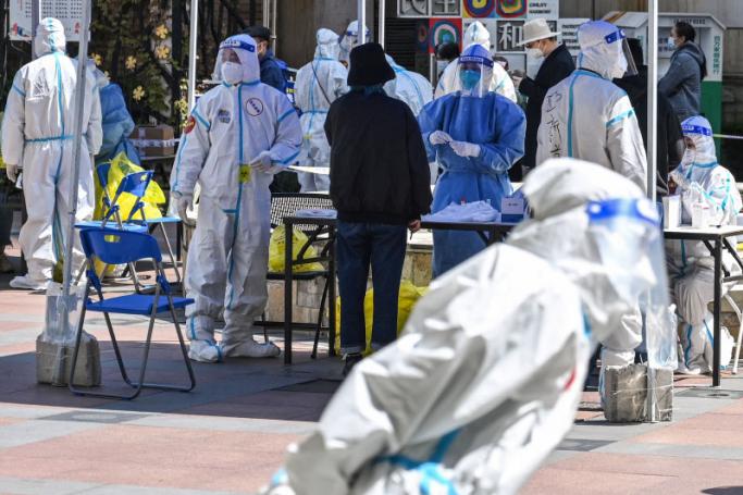 Workers and volunteers look on in a compound where residents are tested for the Covid-19 coronavirus during the second stage of a pandemic lockdown in Jing' an district in Shanghai on April 4, 2022. Photo: AFP