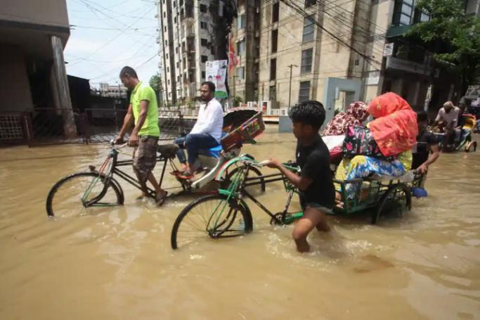 Rickshaw riders at work on an inundated street in Sylhe, Bangladesh, amid floods that have left at least 57 dead in the country and India. Photo: AFP