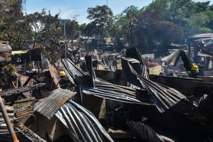 Firemen work at the scene of a fire at an informal settlement inside the campus of the University of the Philippines in Quezon City, suburban Manila on May 2, 2022. Photo: AFP
