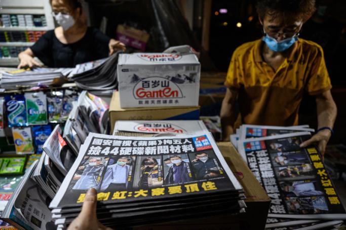 Newsstand employees sort through copies of the latest Apple Daily newspaper before selling them to customers in Hong Kong early on June 18, 2021, after Hong Kong police arrested the chief editor and four executives of the pro-democracy newspaper the day before, raiding its newsroom for a second time in the latest blow to the outspoken tabloid. Photo: AFP