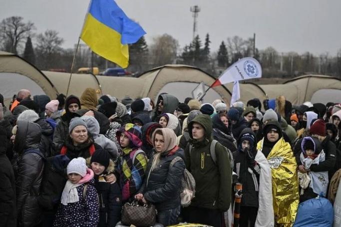 Hundreds of refugees stand in line as they wait to be transferred after crossing the Ukrainian border into Poland, at the Medyka border crossing in Poland. Photo: AFP