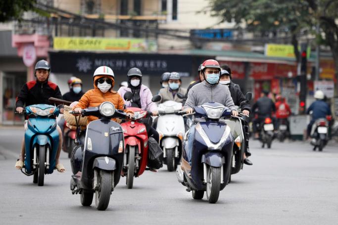 People wearing face masks ride motorbikes on a street in Hanoi, Vietnam, 01 December 2020. Photo: EPA