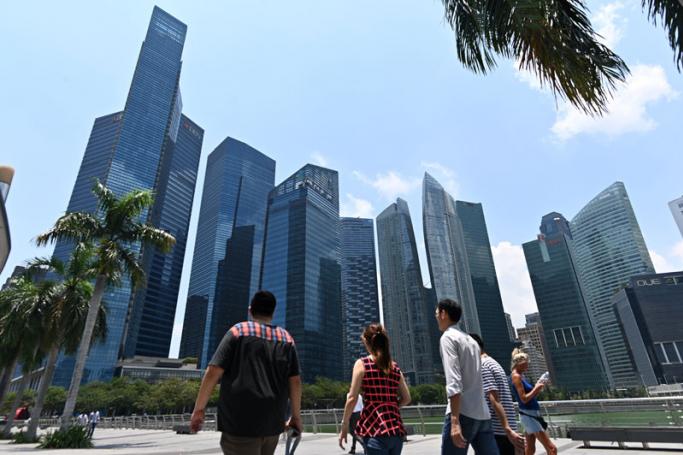 People walk along a promenade with a view of Marina Bay financial centre in Singapore on March 8, 2019. Photo: Roslan Rahman/AFP