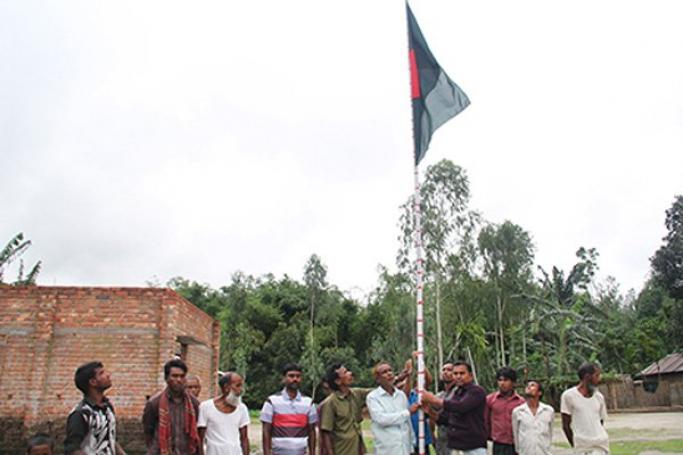 Villagers at Dinbazar, currently an Indian enclave in Bangladesh, pay respect to the Bangladesh national flag earlier this month after the two countries agreed on a plan to exchange enclaves. Photo by Stephan Uttom/UCA News
