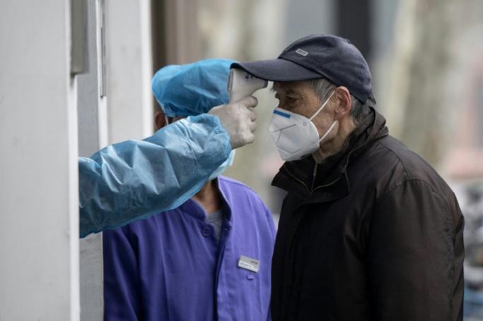 An elderly man wearing a face mask has his temperature checked before entering a community hospital in Shanghai (AFP / NOEL CELIS)