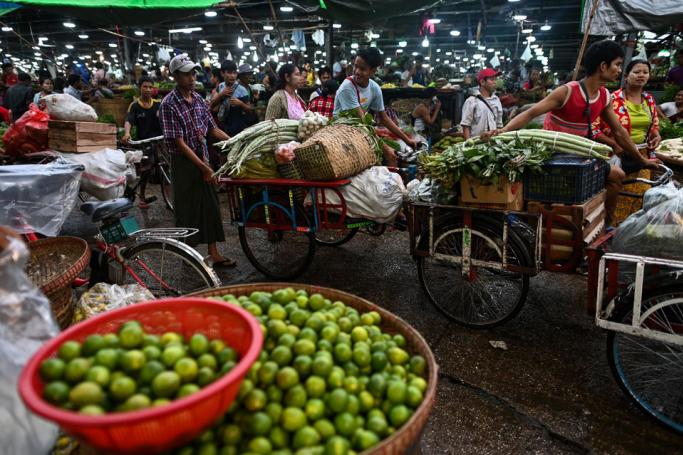 Workers transport fresh vegetables and fruits at a whole sale market in Yangon. Photo: Ye Aung Thu/AFP