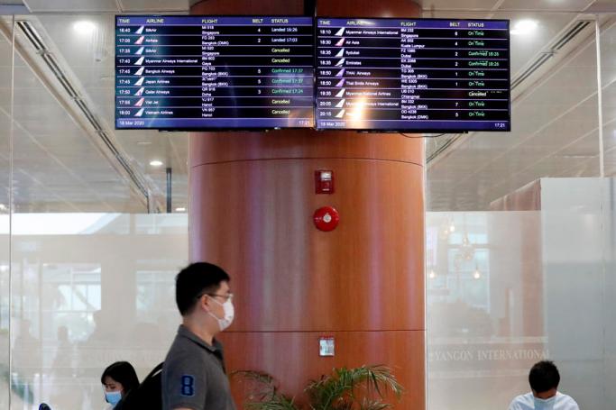 A passenger walks pass a flights information board at the Yangon International Airport in Yangon, Myanmar, 18 March 2020. Photo: Nyein Chan Naing/EPA