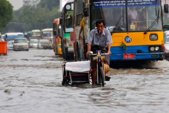 Myanmar man rides a trishaw through a flooded road at downtown area of Yangon. Photo: EPA