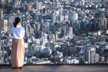 A woman looks out from an observatory deck in Tokyo on September 23, 2021. Charly TRIBALLEAU / AFP