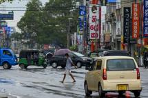 A man holding an umbrella crosses the road in Colombo on October 1, 2021, after the government lifted the lockdown that was earlier imposed to curb the spread of the Covid-19 coronavirus. Ishara S. KODIKARA / AFP