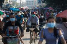 (File) Commuters wearing face masks amid concerns over the spread of the COVID-19 coronavirus make their way on bikes in the Hlaing Tharyar township on the outskirts of Yangon on May 16, 2020. Photo: AFP