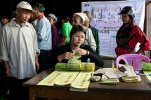 (File) A staff member of Myanmar Election Commission prepares ballot papers as people wait during advance voting at a polling station of Myit Kyi Na township in Kachin State, northern Myanmar, 07 November 2015. Photo: EPA