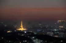 The light from pagoda and buildings illuminate the misty sky after the last sunset of the year in Yangon, Myanmar. Photo: Lynn Bo Bo/EPA