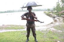 A Bangladeshi border guard holds an umbrella as he stands guard in the rain at the Myanmar-Bangladesh border in MaungDaw township, Rakhine State, western Myanmar, 08 June 2015. Photo: Nyunt Win/EPA

