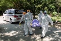(FILE) In this file photo taken on November 25, 2020, volunteers wearing personal protective equipment (PPE) carry the body of a person suspected of dying from the Covid-19 coronavirus for their burial in the Hteinbin Muslim Cemetery in Yangon. Photo: Sai Aung Main/AFP
