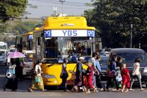 People walk in front of a YBS bus at a traffic light during rush hour in Yangon. Photo: EPA