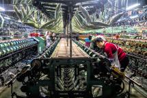 A woman works in a silk clothing factory on modern production machinery for silk clothing in Shengze, Jiangsu province, China. Photo: EPA