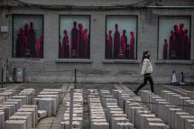 (File)  A woman wearing a medical face mask walks on an empty street next to the 798 Art District in Beijing, China, 06 March 2020. Photo: EPA