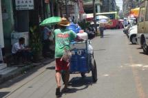 A man pushes a cart loaded with water bottles on a street in Yangon. Photo: Htet Hkaung Linn/Myanmar Now
